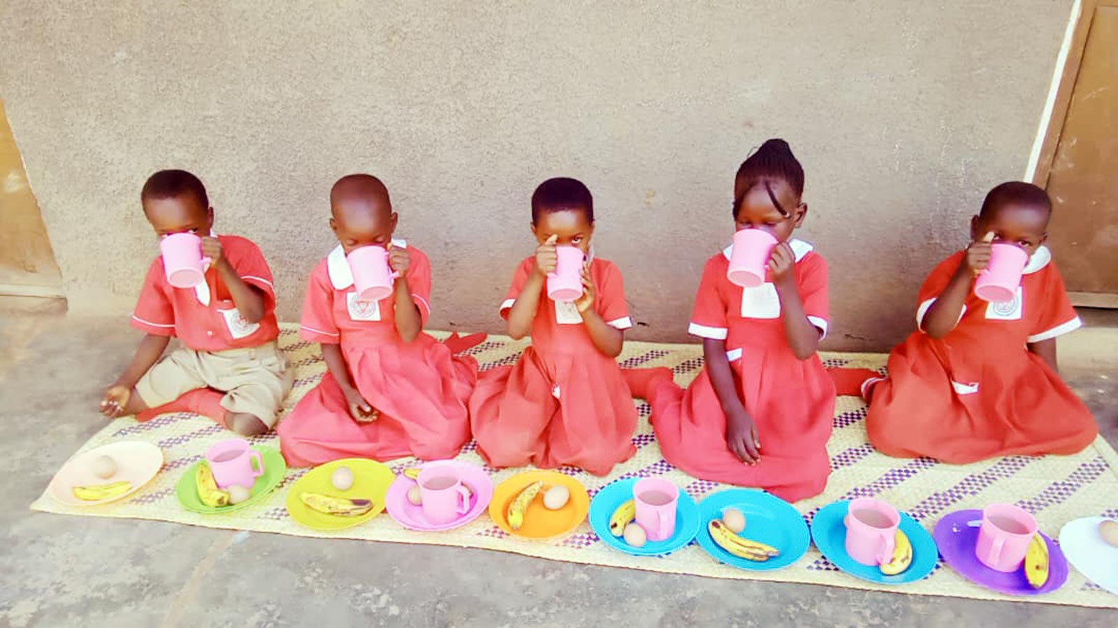 At Holt's partner organization in Uganda: children eat their lunch with colorful plates.