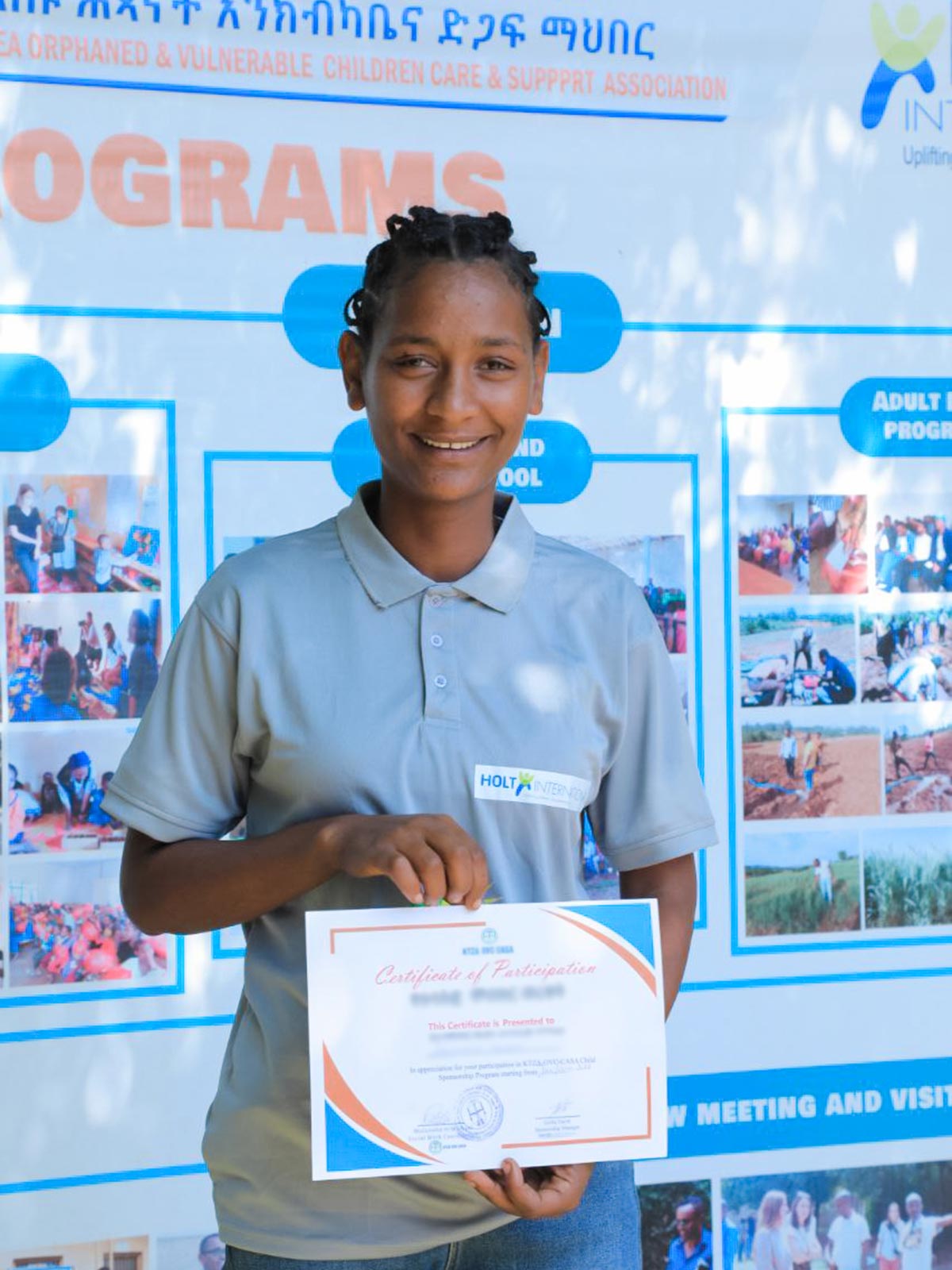 A young woman holds a certificate of educational achievement made possible by a Gift of Hope