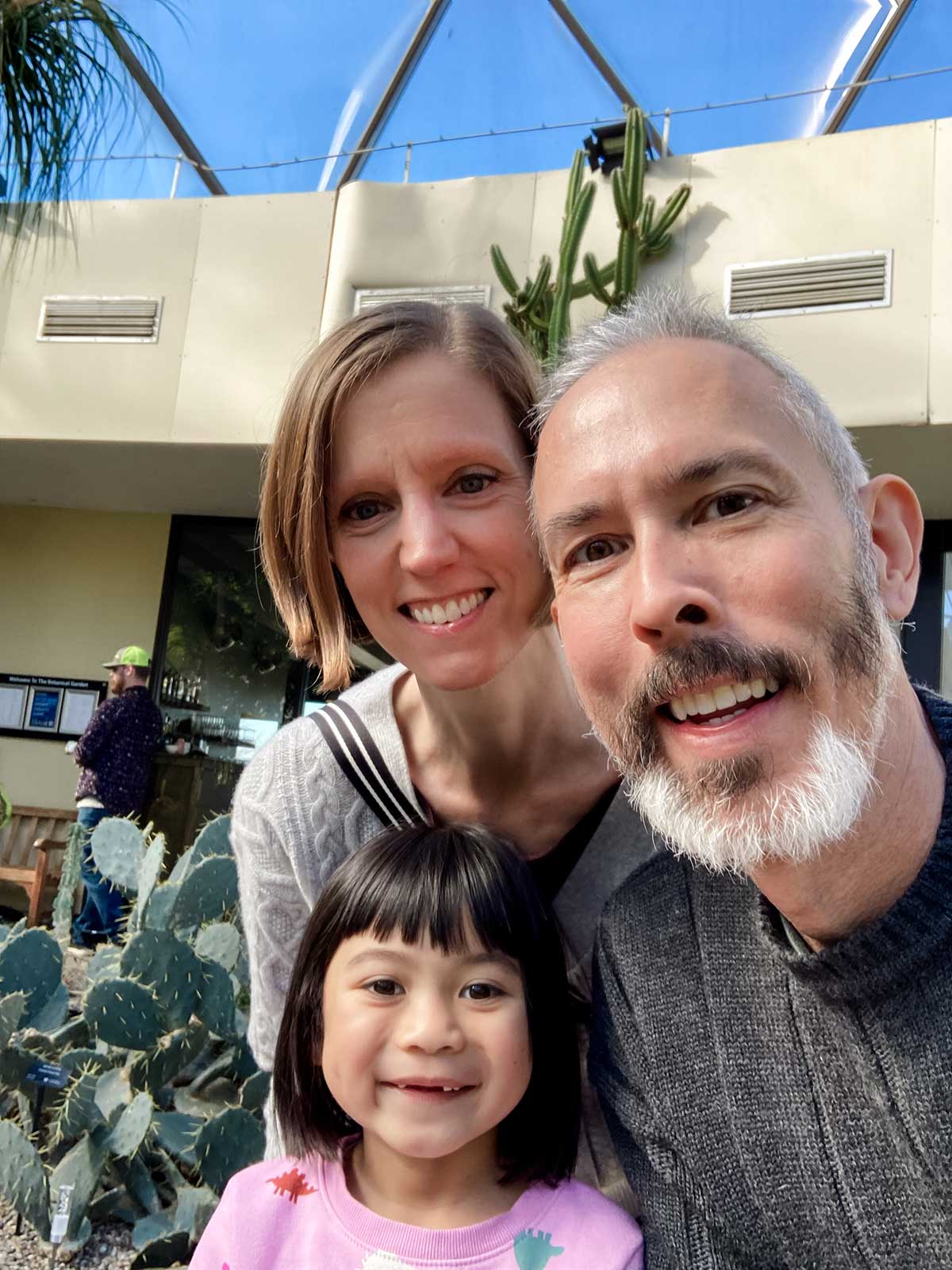 adoptive parents smile with their adopted child from Thailand