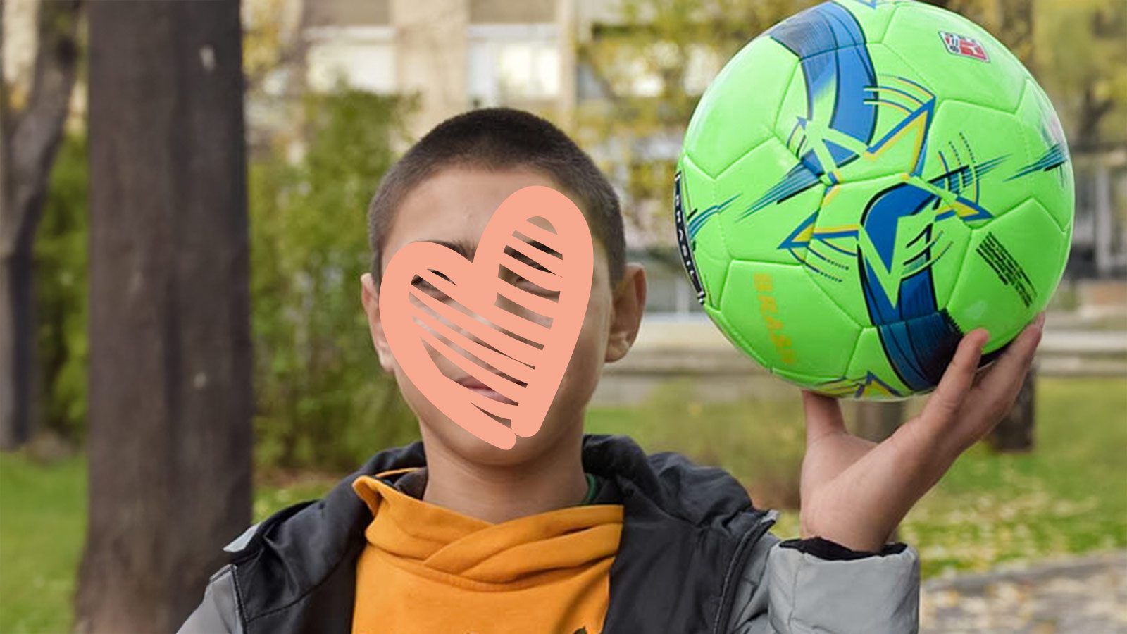 A waiting child holds a soccer ball.