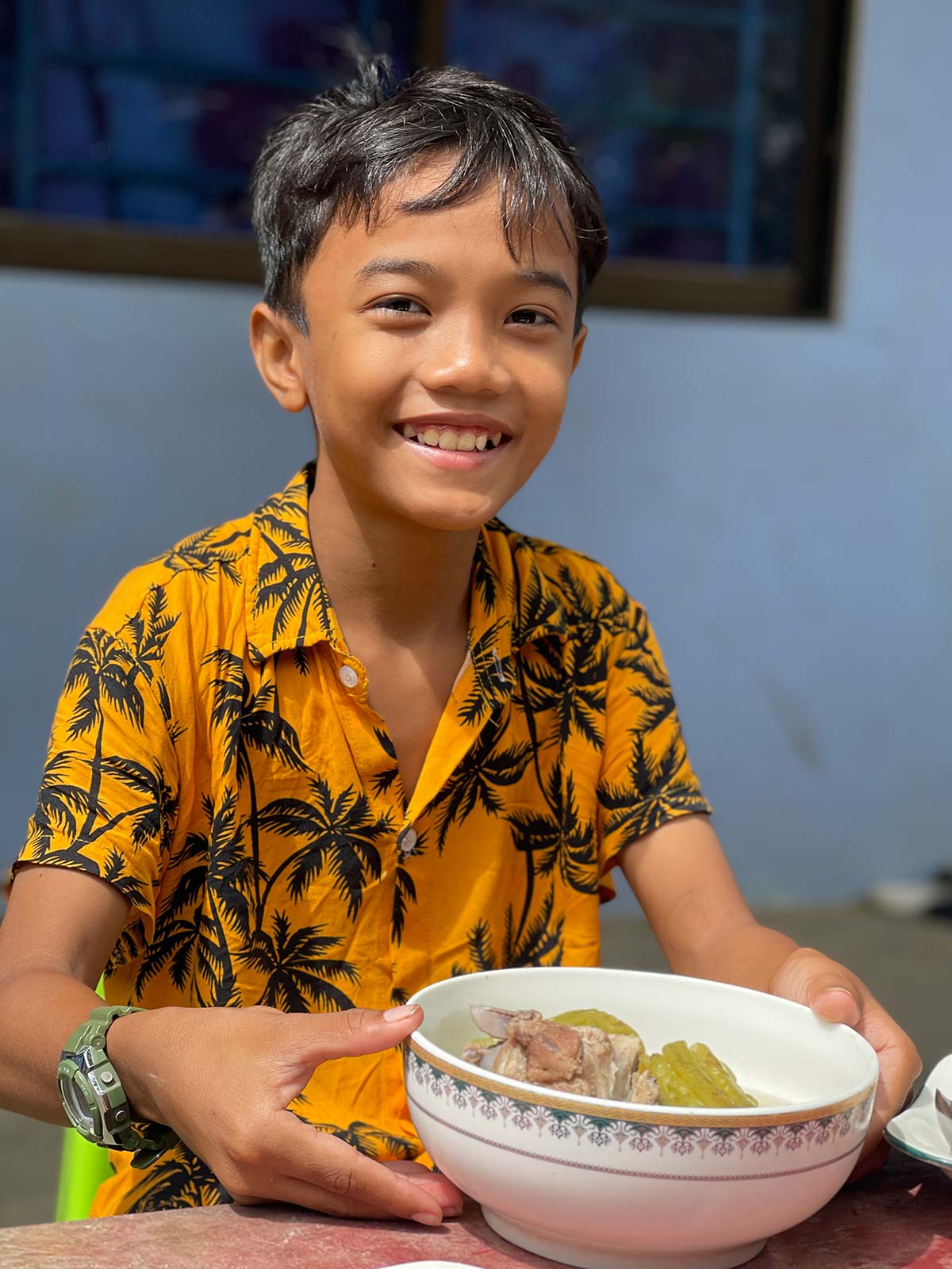 a boy smiles with his meal, provided through gifts of hope