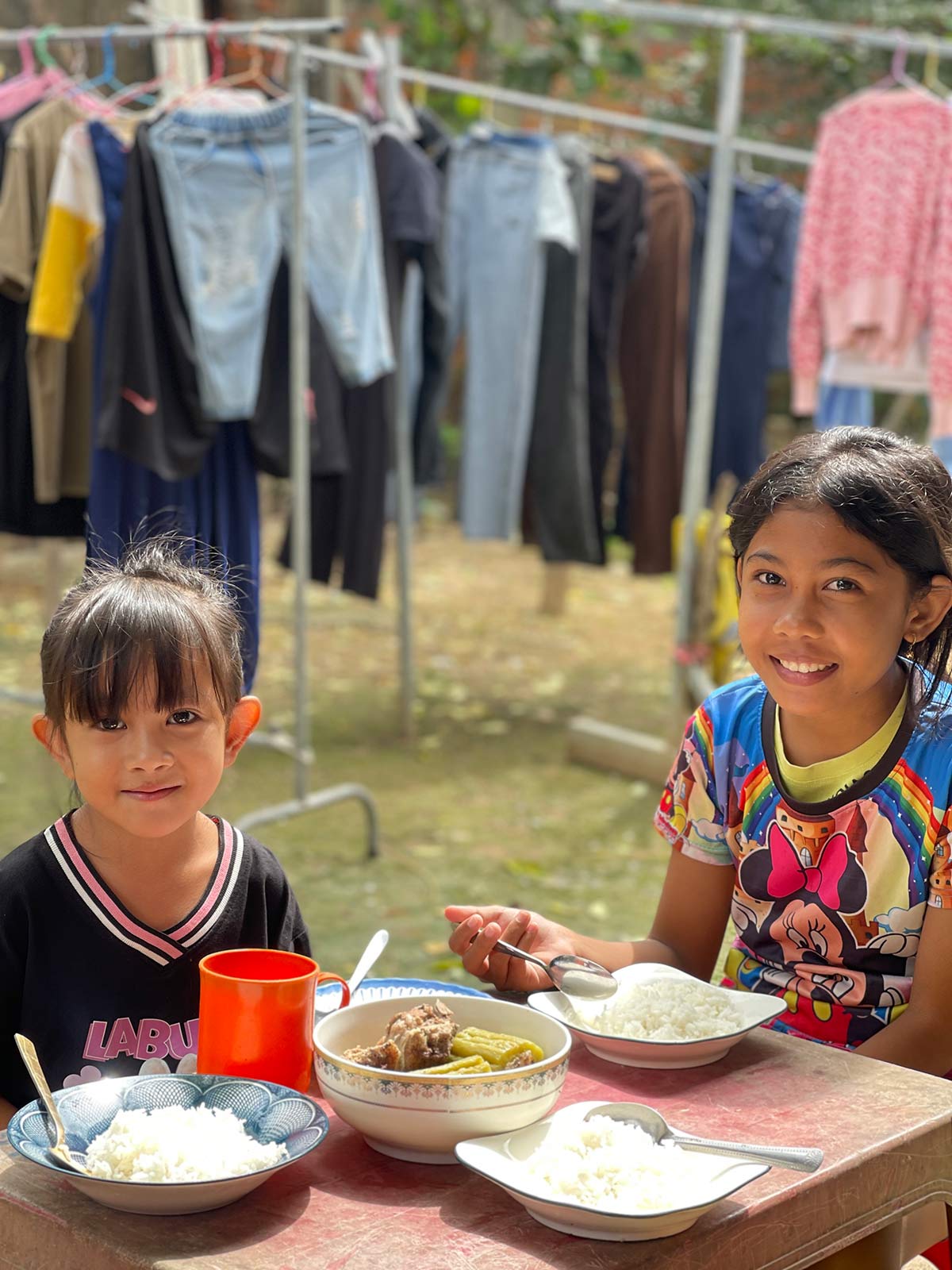 Two girls smile with their meals provided by food assistance 