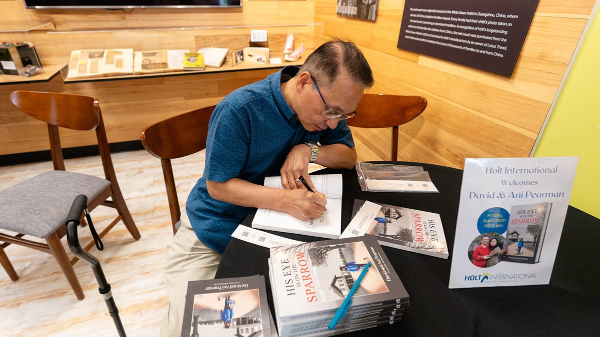 an adoptee and authors signs copies of his book "The Eye is on the Sparrow"