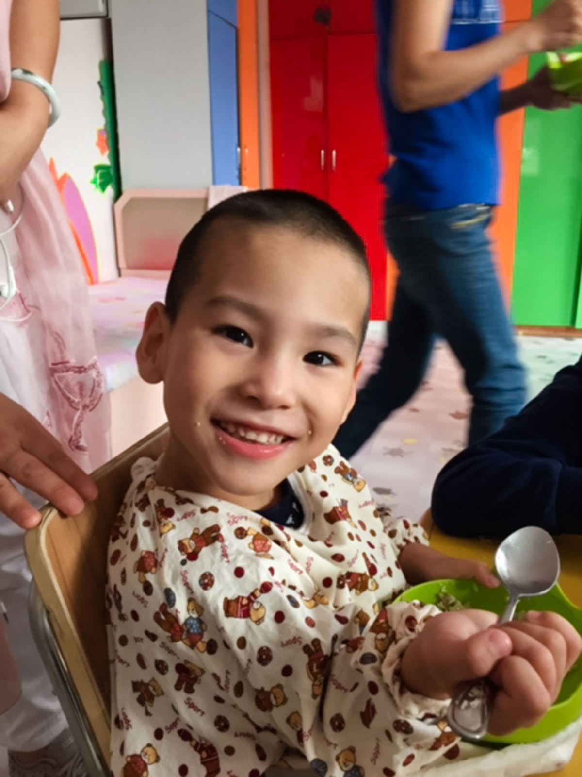 a boy with cerebral palsy in china smiles while holding a spoon