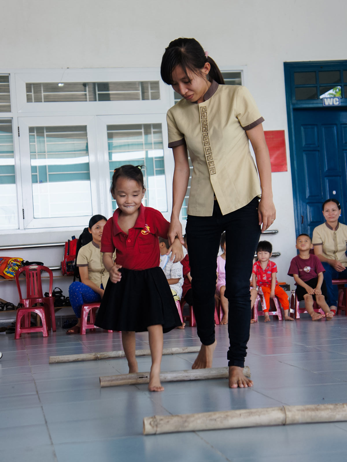 a child who is deaf and blind walks with the help of a caregiver in vietnam