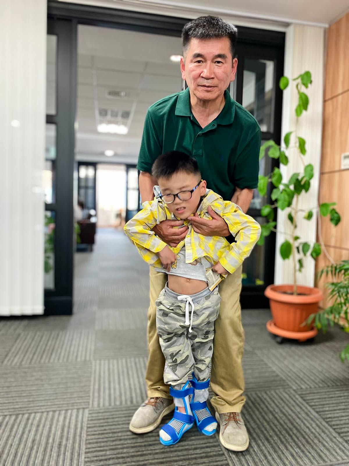 a child with cerebral palsy in mongolia takes his first steps with the help of a caregiver