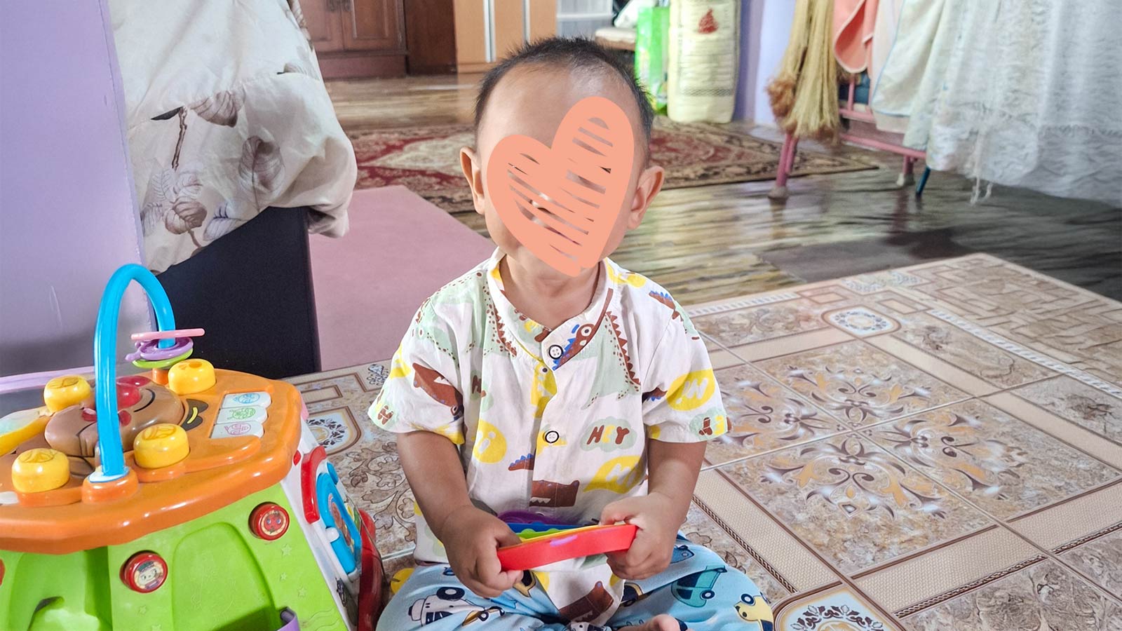 A waiting child holds a toy while sitting on the ground