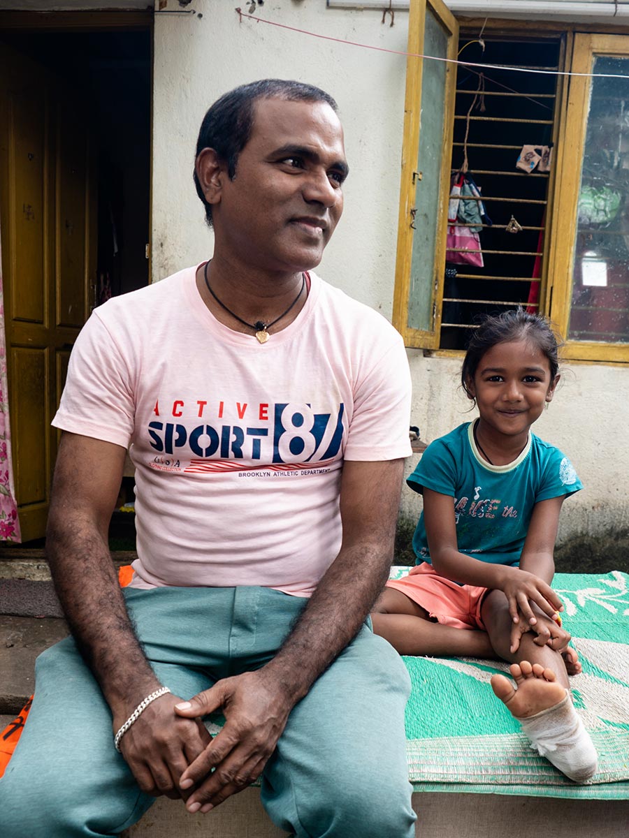 A father and son sit on an outside bench and share their story in India