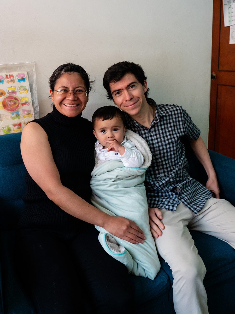 a mother and father hold their infant on a couch in Colombia