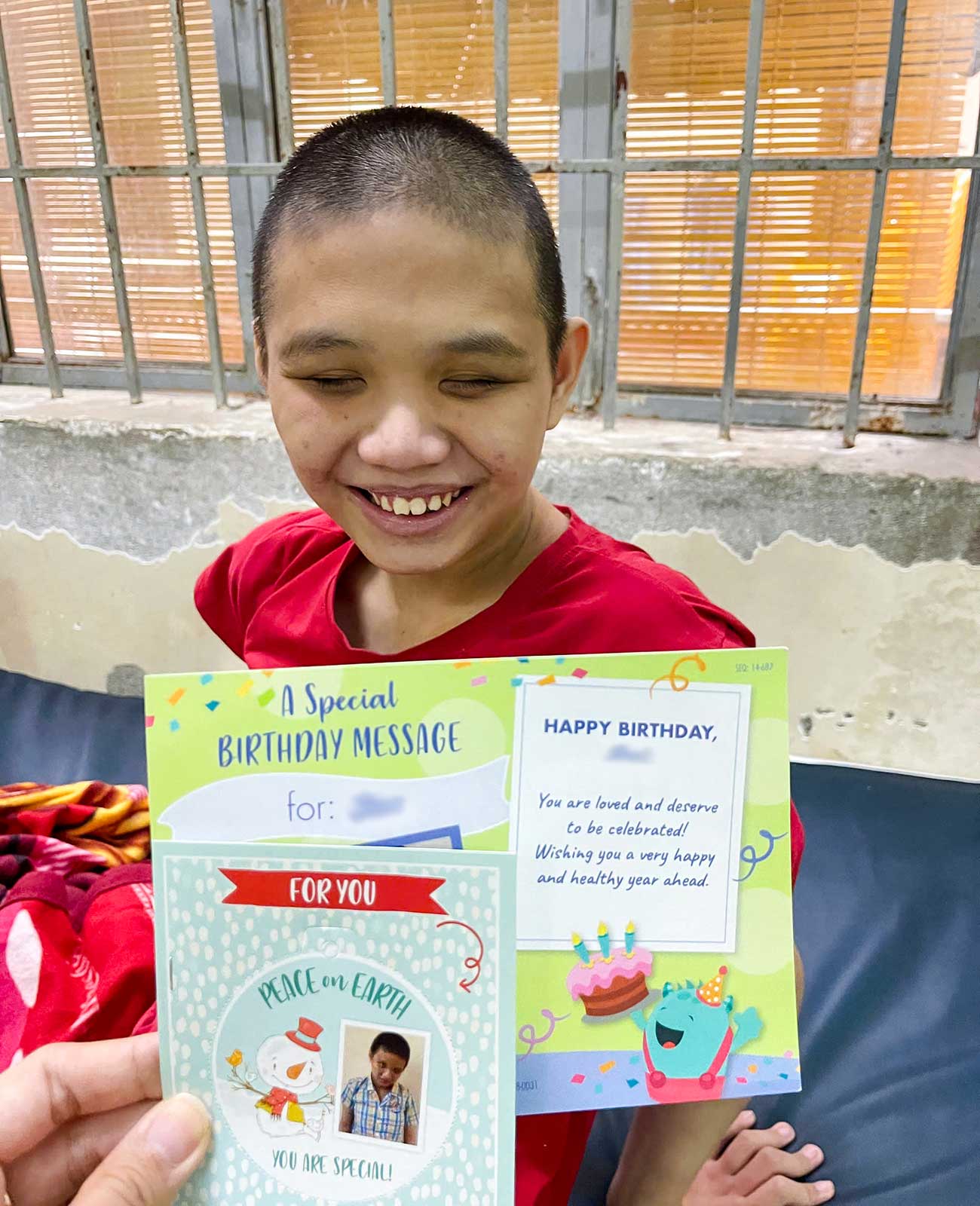 a child with special needs smiles with her birthday and christmas card from a sponsor