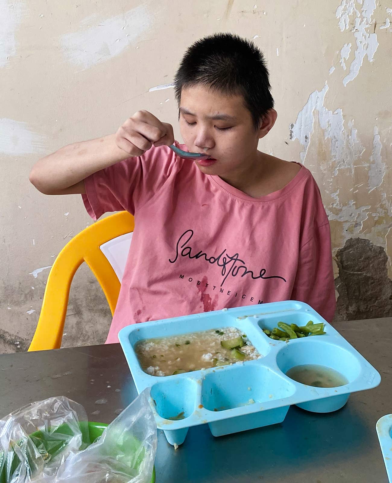 A girl with special needs in Vietnam uses a spoon to feed herself a meal