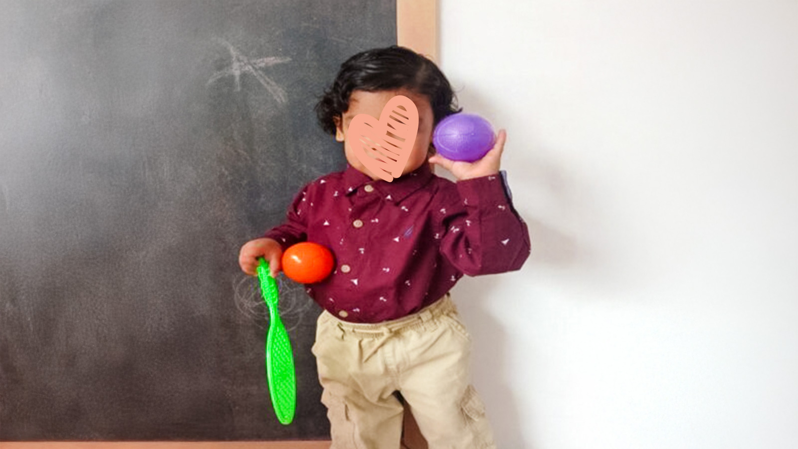 a waiting child who needs a family holds a ball by a chalkboard