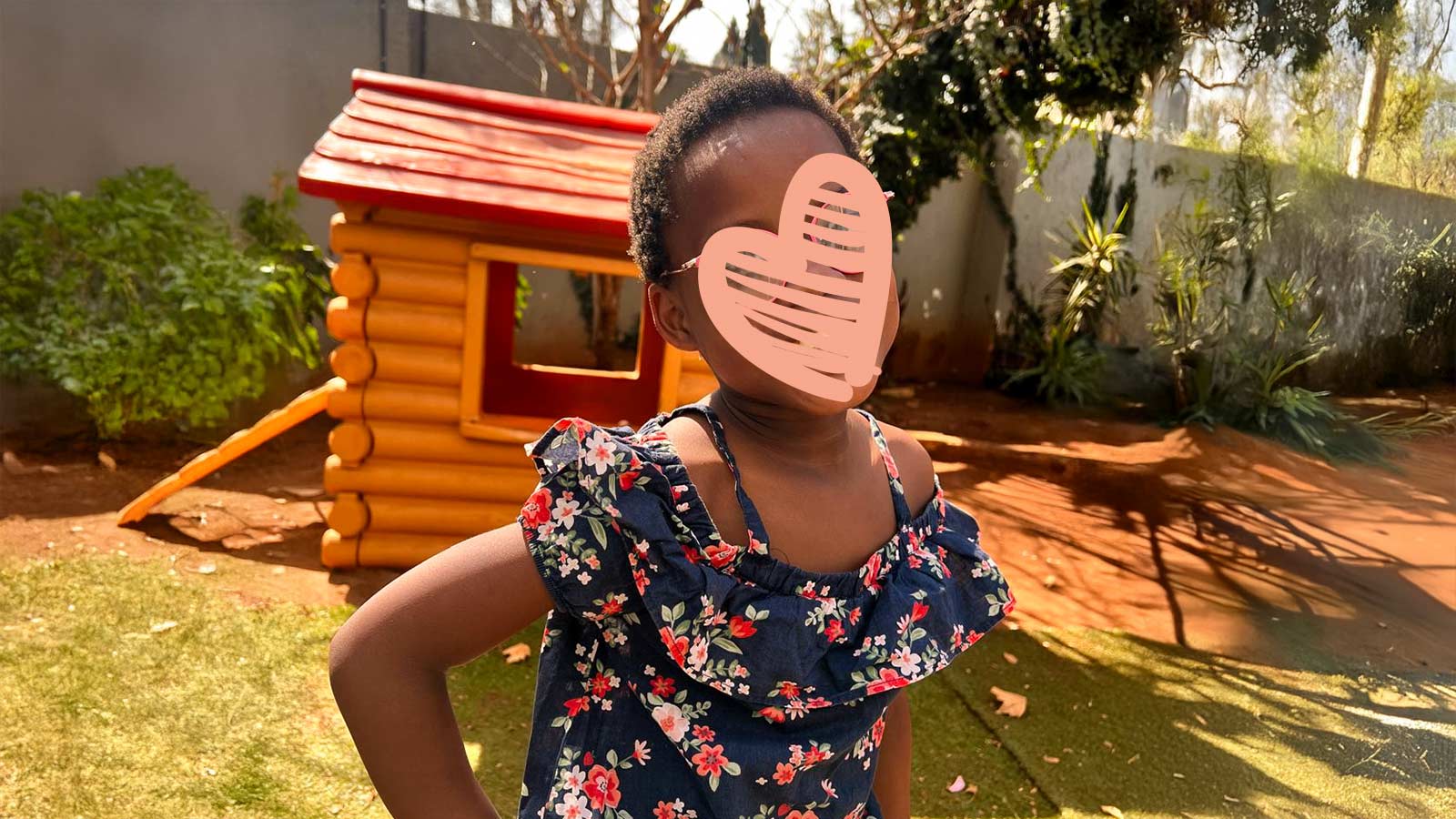 a waiting child smiles outside next to a play house