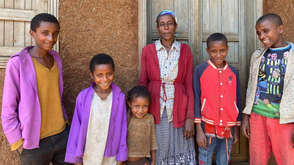 Ayana and her family stand in front of their house in Ethiopia with smiles because you supported their education!