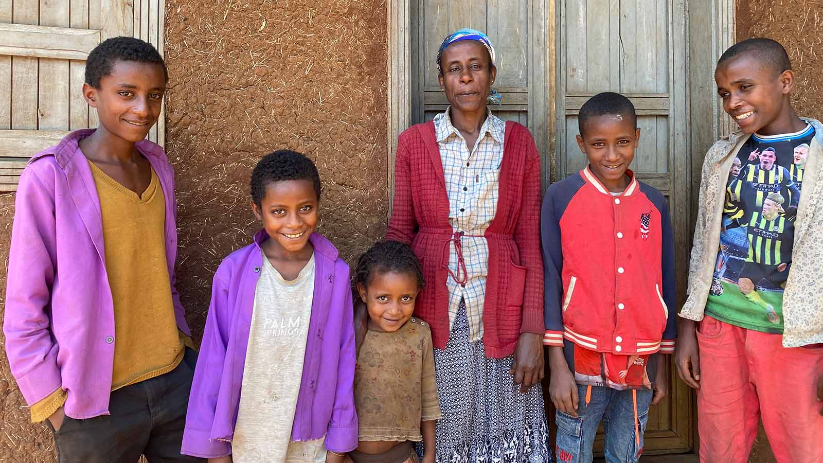 Ayana and her family stand in front of their house in Ethiopia with smiles because you supported their education!
