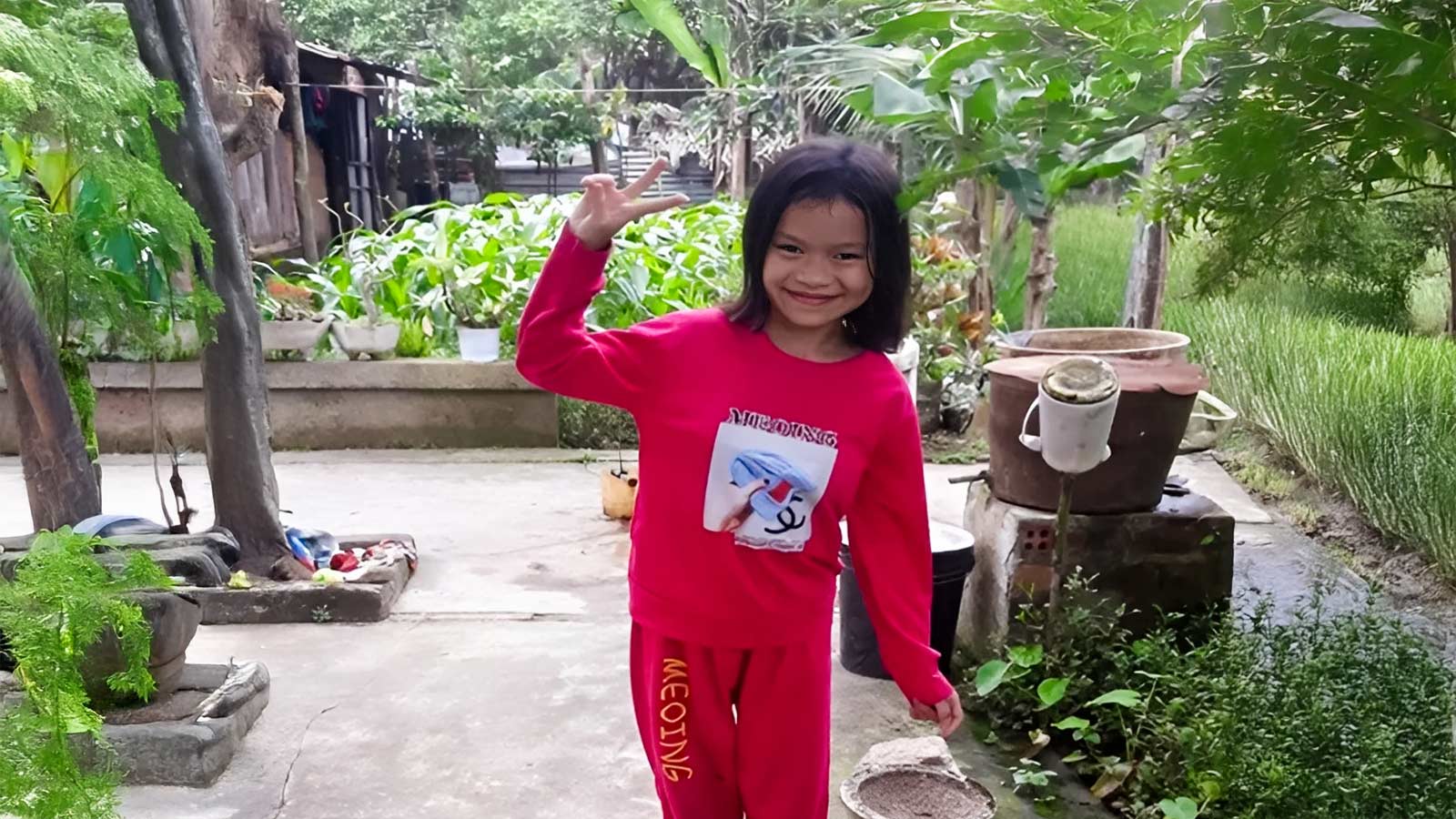 Thuy smiles outdoors in Vietnam because your educational support is allowing her to go to school!