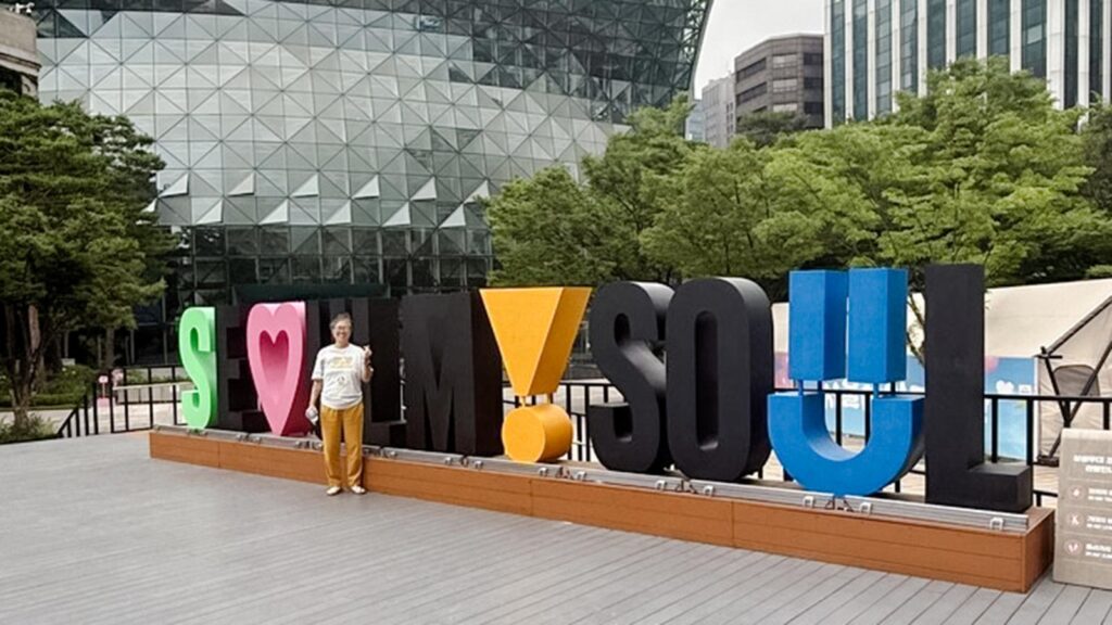 korean adoptee standing next to Seoul, Korea sign