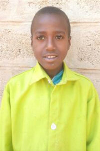 Sponsored child Tigabu in Ethiopia smiling in a bright green shirt.