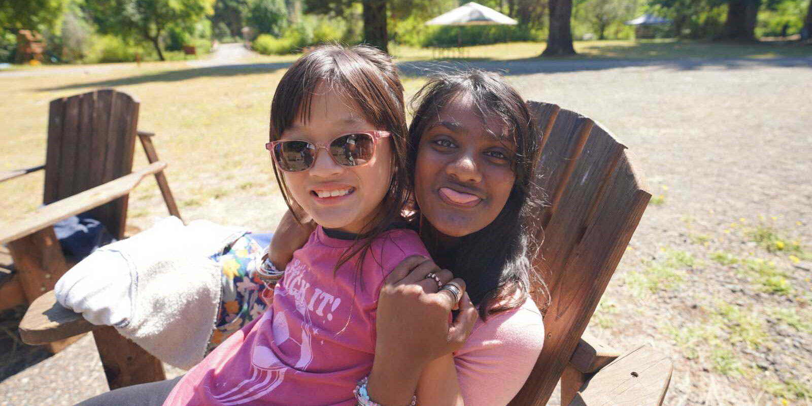 Holt campers in pink shirts and sunglasses smiling on a lawn chair