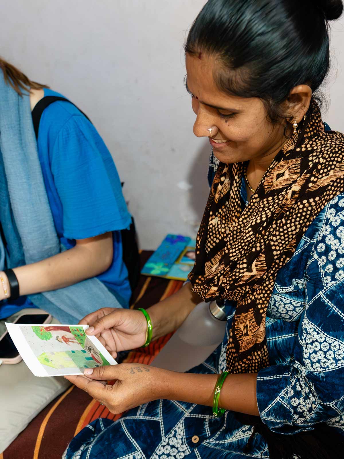 a mother of a sponsored child holds the drawing her daughter made of her dream home