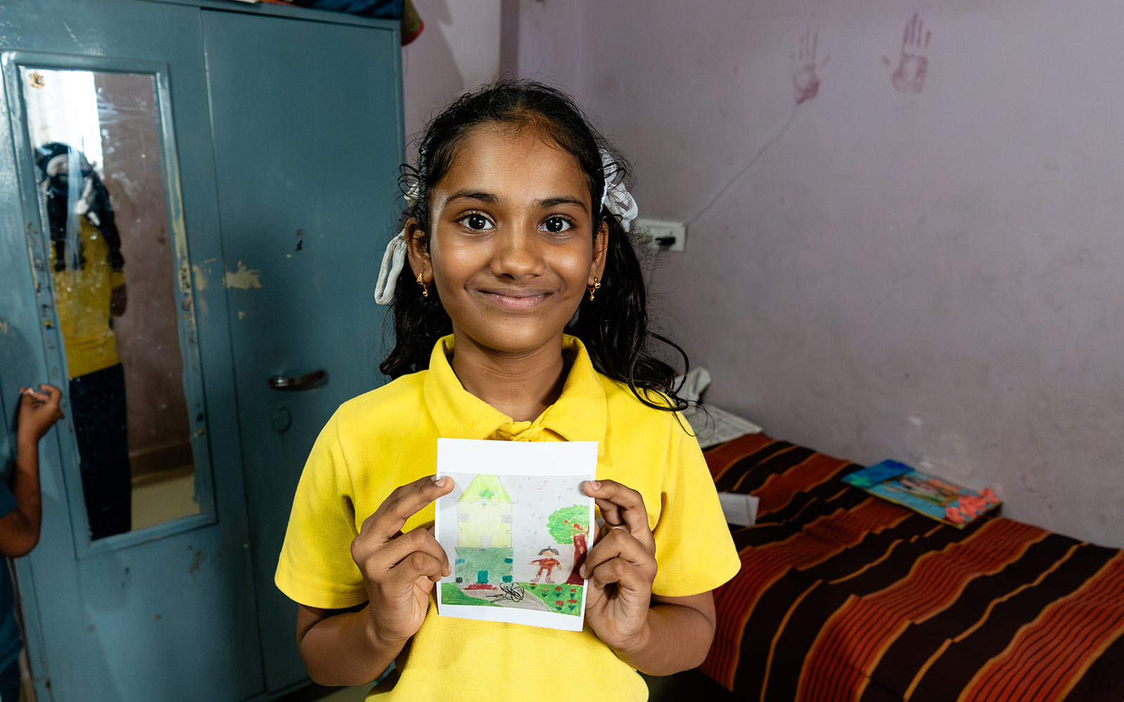 a sponsored girl holds the drawing she sent to sponsors of her dream home