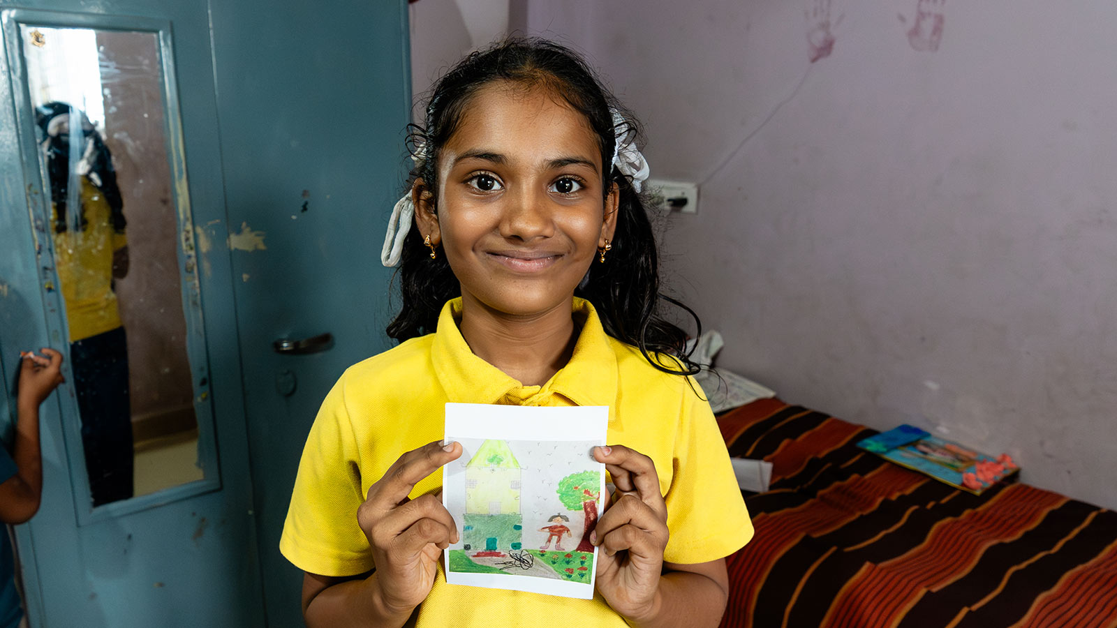 a sponsored girl holds the drawing she sent to sponsors of her dream home