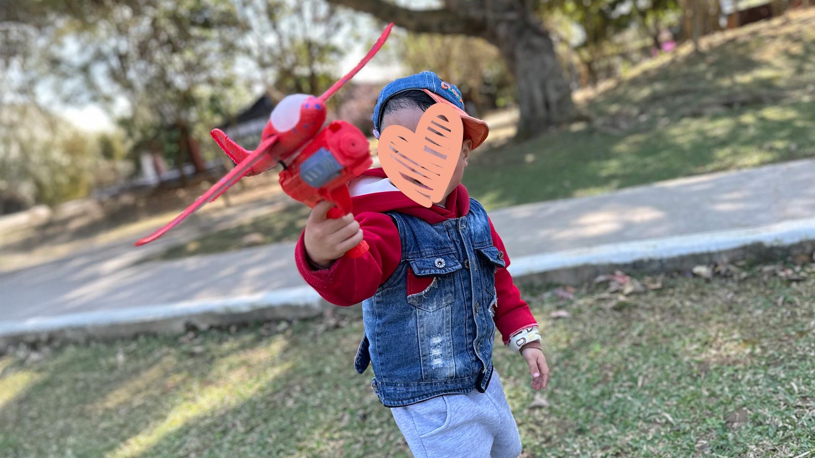 a waiting child holds an airplane with a heart over his face