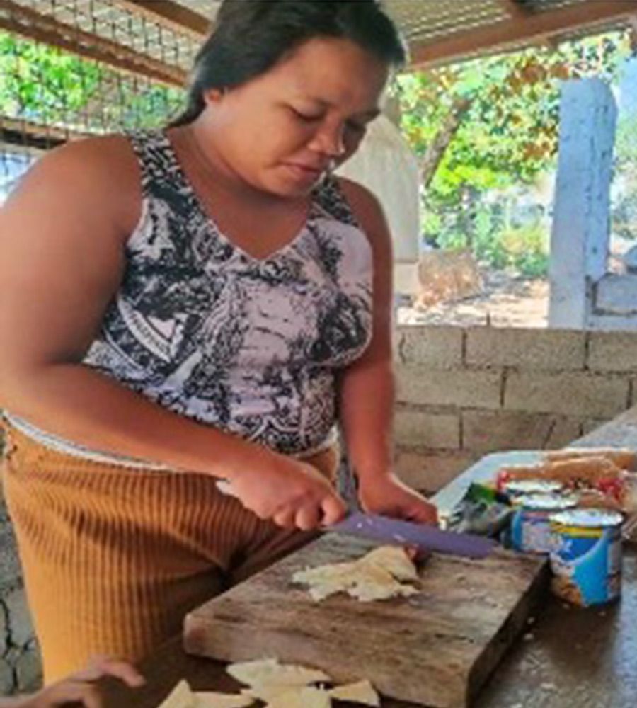 a woman chops a vegetable to provide school lunch at a holt-supported early education center