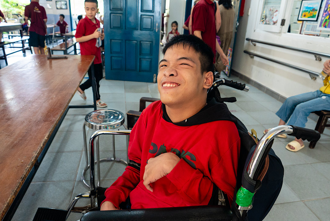 A boy in a wheelchair with cerebral palsy smiles at the camera