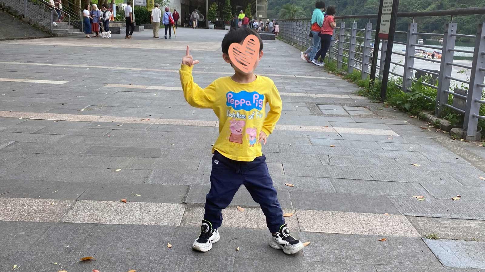 a waiting child stands in a yellow shirt with a heart over his face