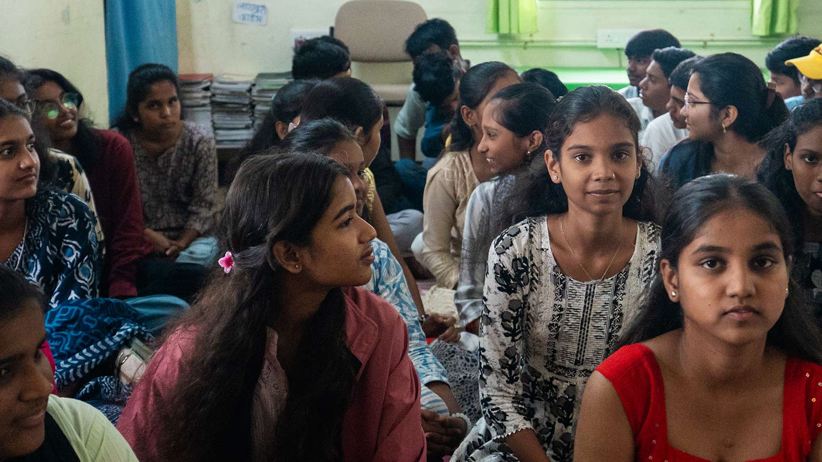 a group of girls in India sit on the floor, sharing their career and educational goals
