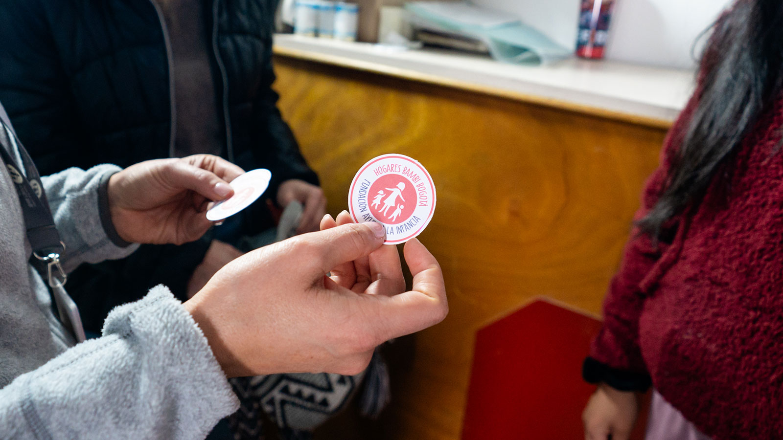 a woman holds out a sticker that reads "hogares bambi," within a red circle