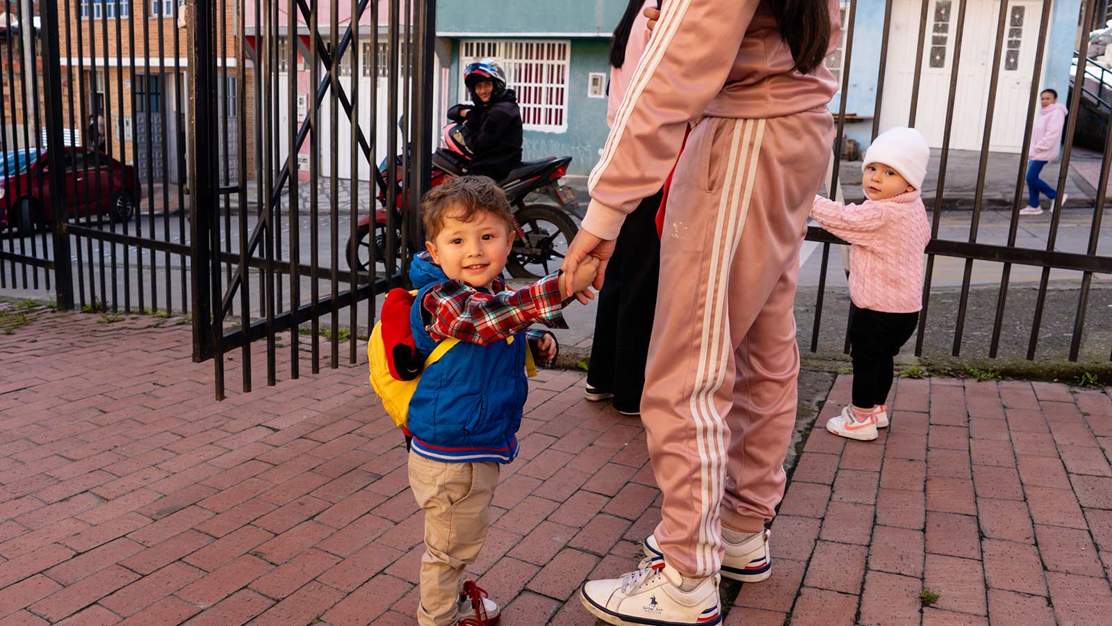 a mother holds her son's hand at a local childcare center in colombia