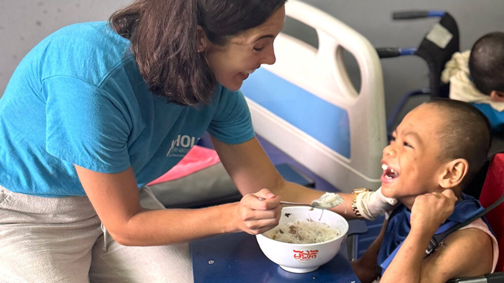 Child Nutrition Program manager Julia Hayes demonstrates how to properly feed a child with a disability at an orphanage in Cambodia.
