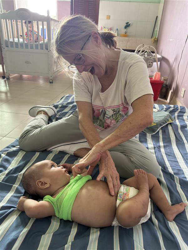 Feeding specialist Rae Catt working a baby during a CNP training at an orphanage in Cambodia