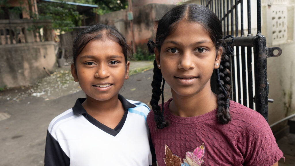 Two little girls in India standing out side in the street