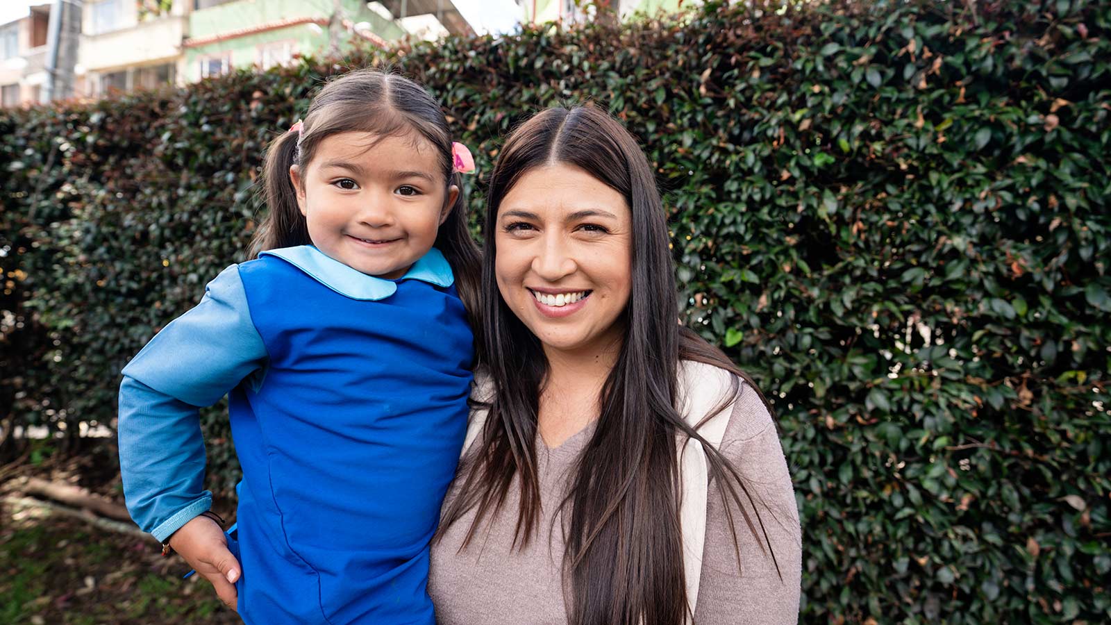 a little girl and her mother smile outside a children's center in colombia