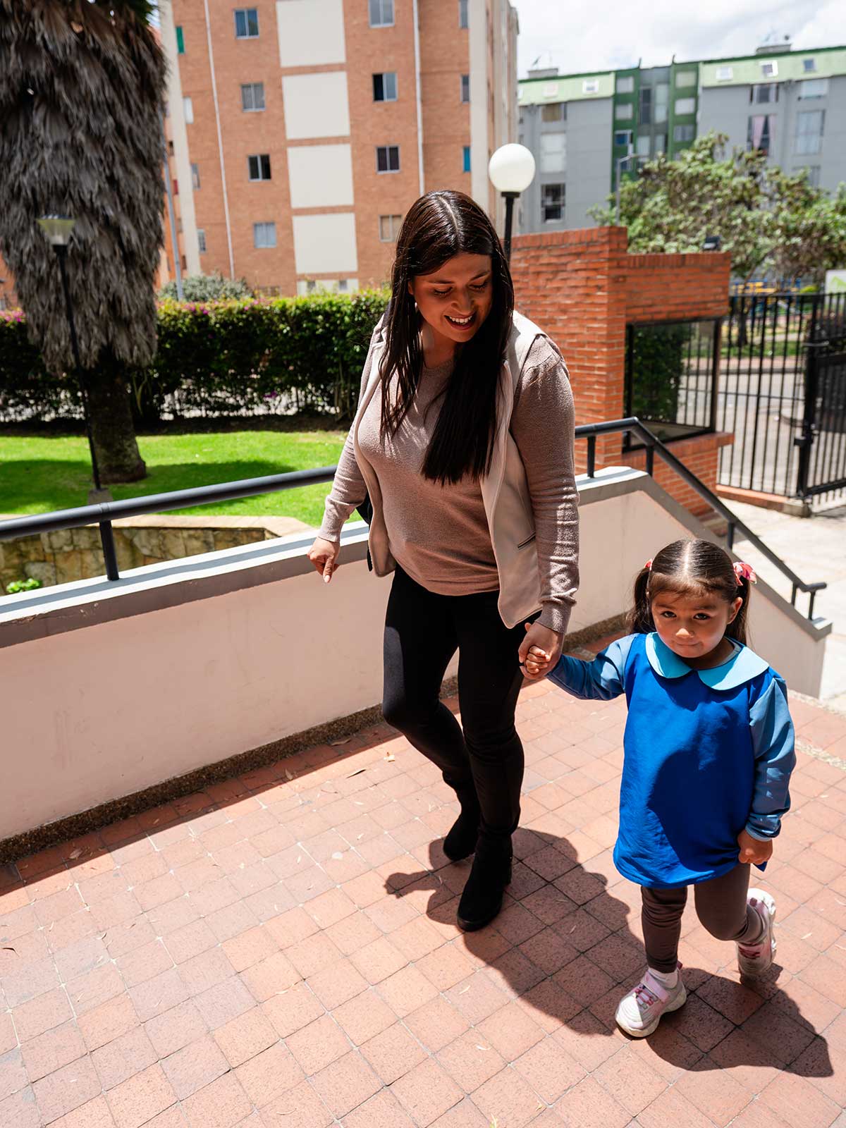 a mom leads her daughter by the hand to the entrance of a children's center
