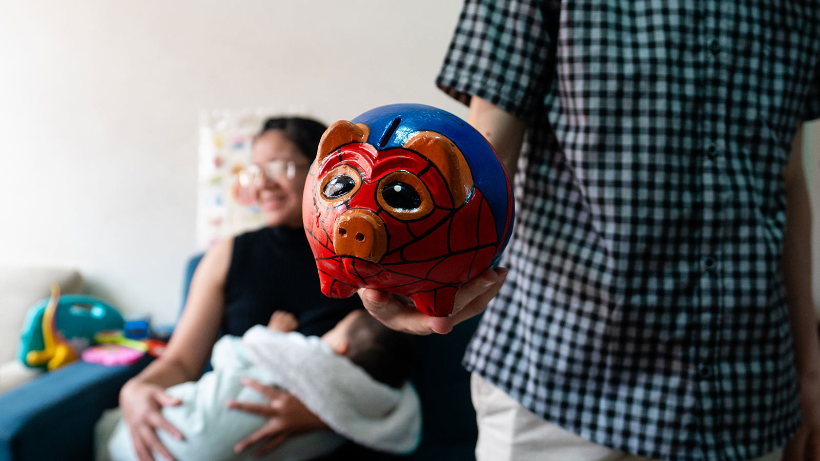 a man holds out a spiderman piggy bank