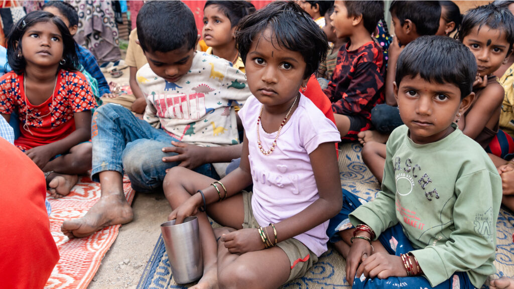 A group of children sitting in a migrant camp in India