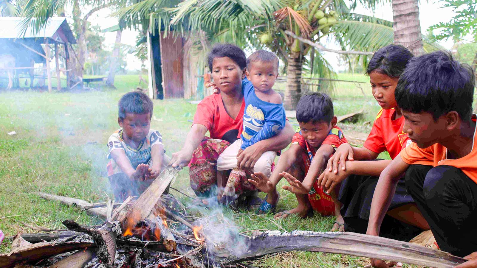 a mother and her children gather around a fire, trying to stay warm in Cambodia winter