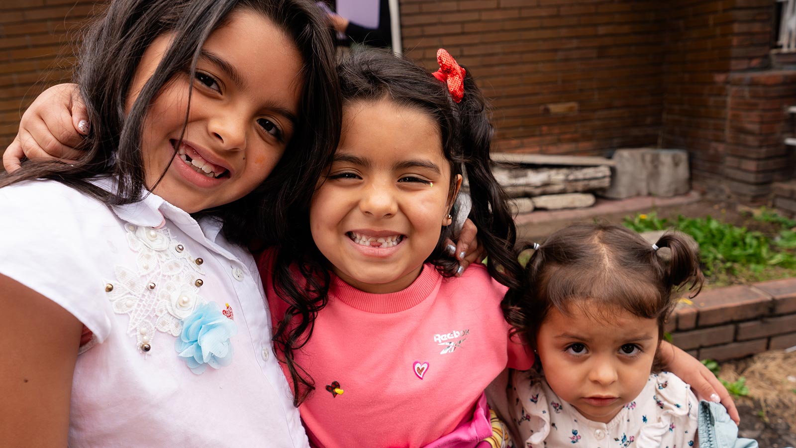 three sisters smile in colombia with their new coats and shoes, thanks to holt donors