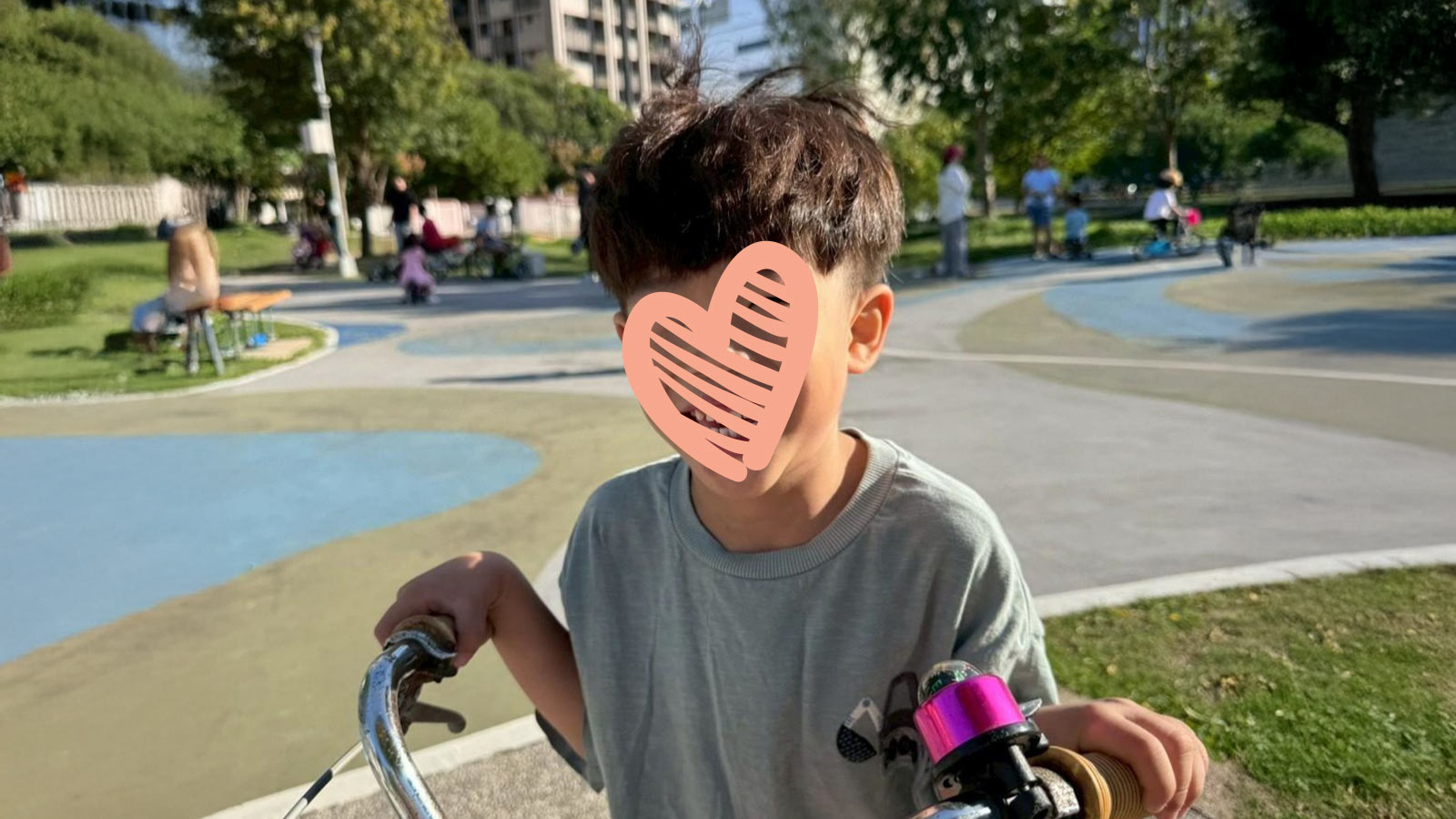 a boy who is waiting for a family stands outside with his bike