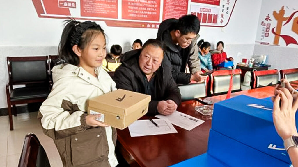 a girl wears her new winter coat and holds out her new shoes in a box