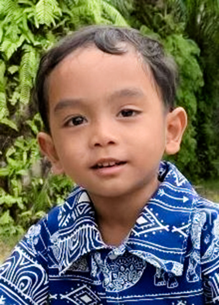 a sponsored boy wearing a button down shirt looks into the camera