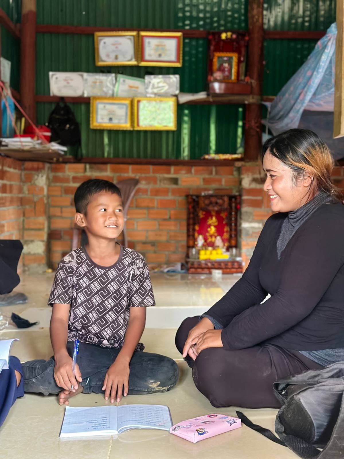 a mother looks at her son and they smile at eachother, sitting on the floor of their newly renovated home