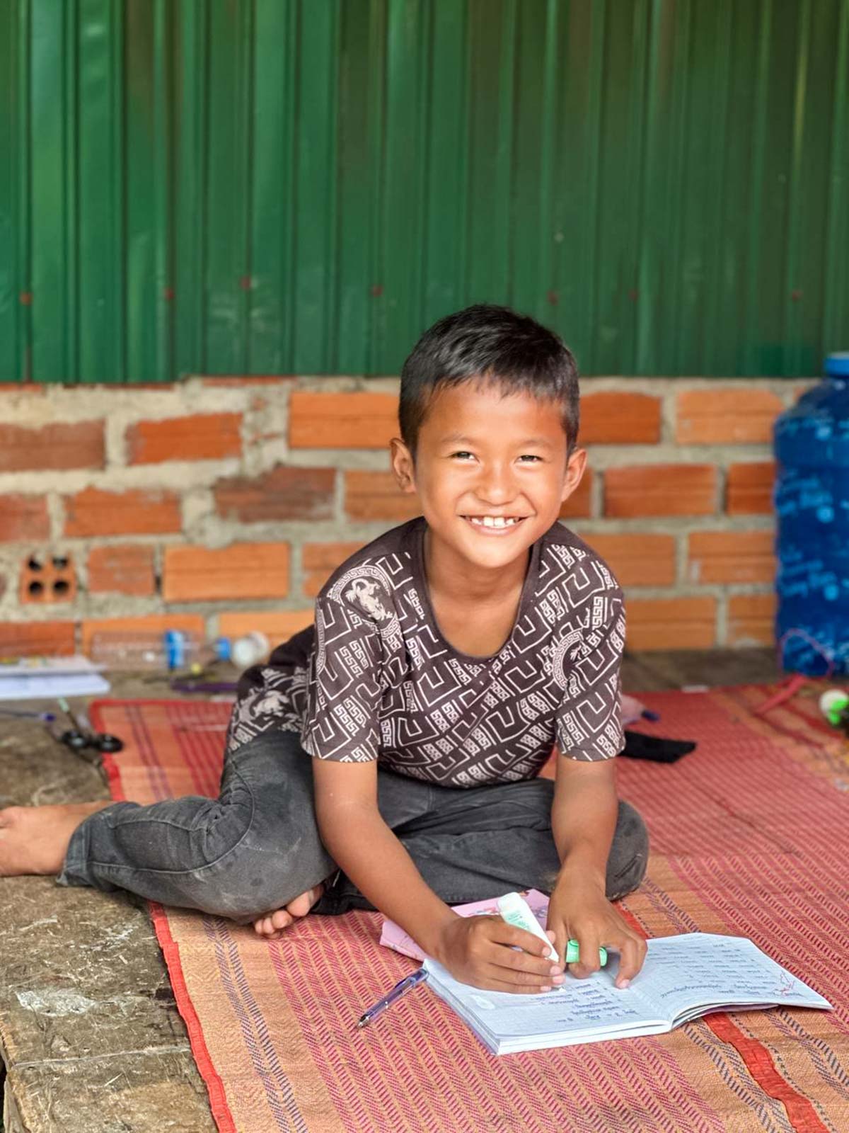 a little boy sits on the floor and works on his schoolwork inside his newly renovated home