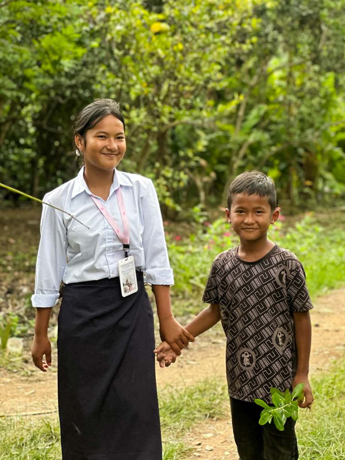 two sponsored siblings hold hands outside in Cambodia
