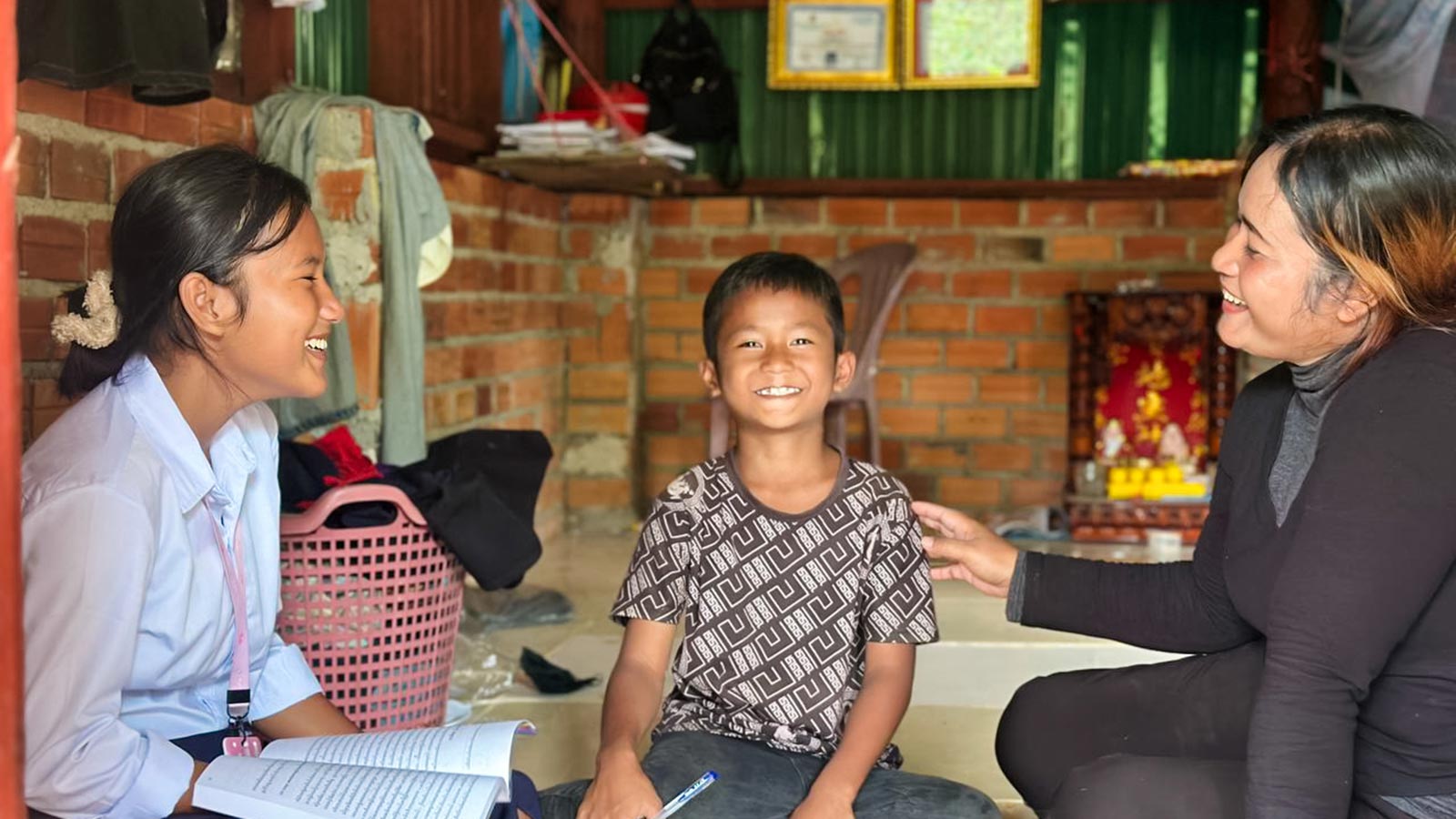 a family of three smiles together in a safe, warm home thanks to sponsor support
