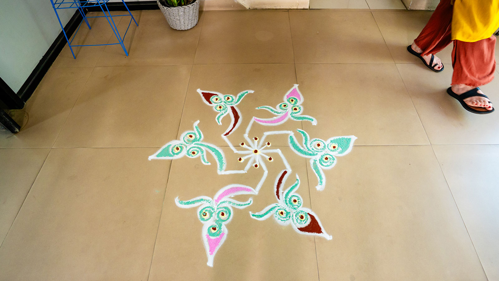 a beautiful rangoli design made with teal, pink and burgundy powders